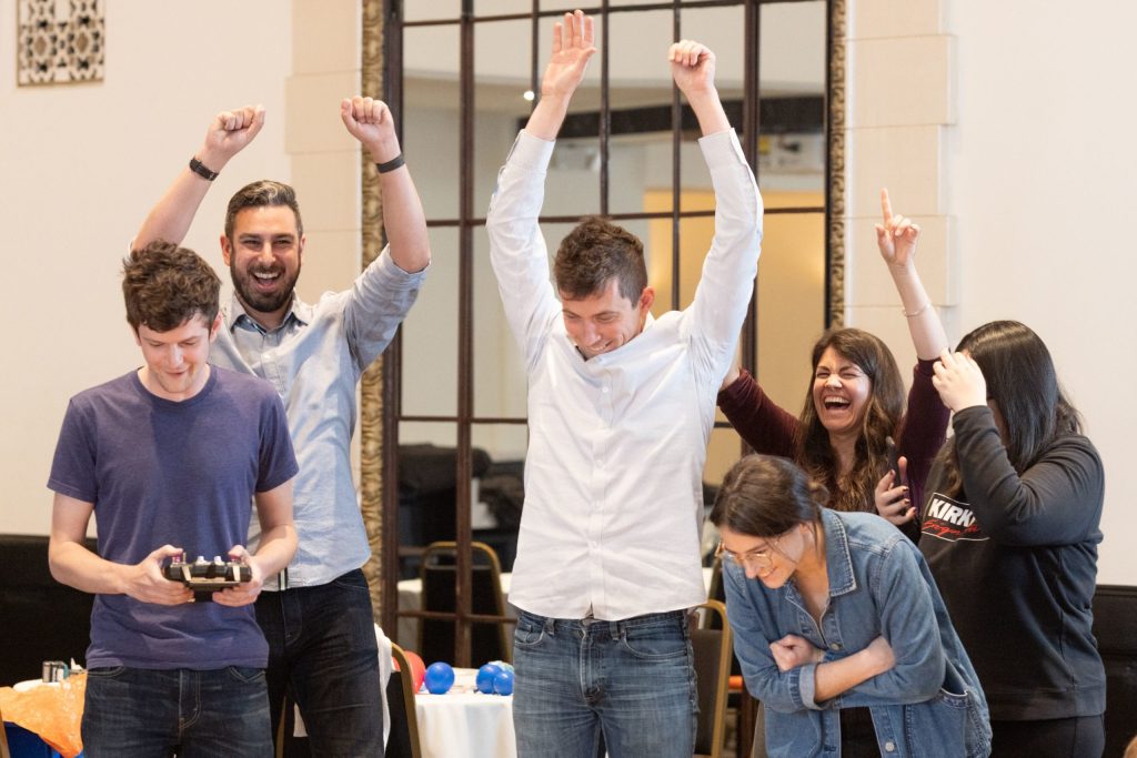 Team celebrating a win, arms raised in excitement. Group event.
