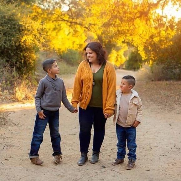 Mother and two sons walking on a path in autumn, surrounded by golden trees.