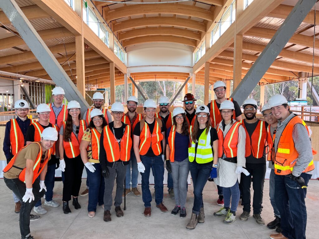 Group of construction workers with hard hats and safety vests indoors.