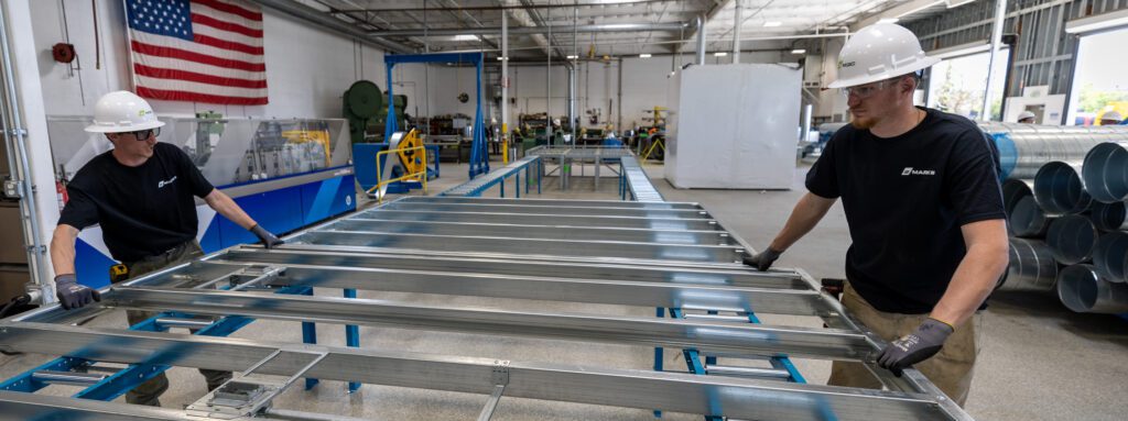 Workers assemble metal framing in a manufacturing facility, supporting Boldt's healthcare clinic roadmap.