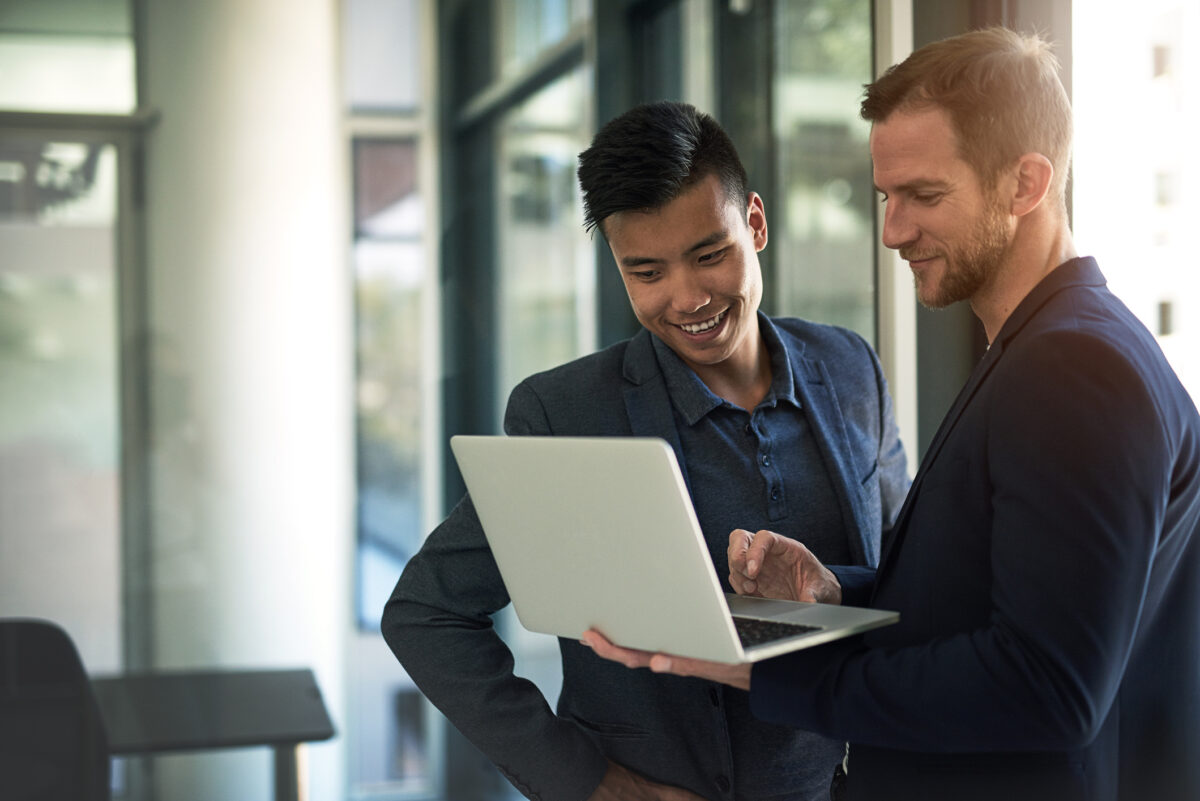 Two colleagues reviewing preconstruction software on a laptop in an office.