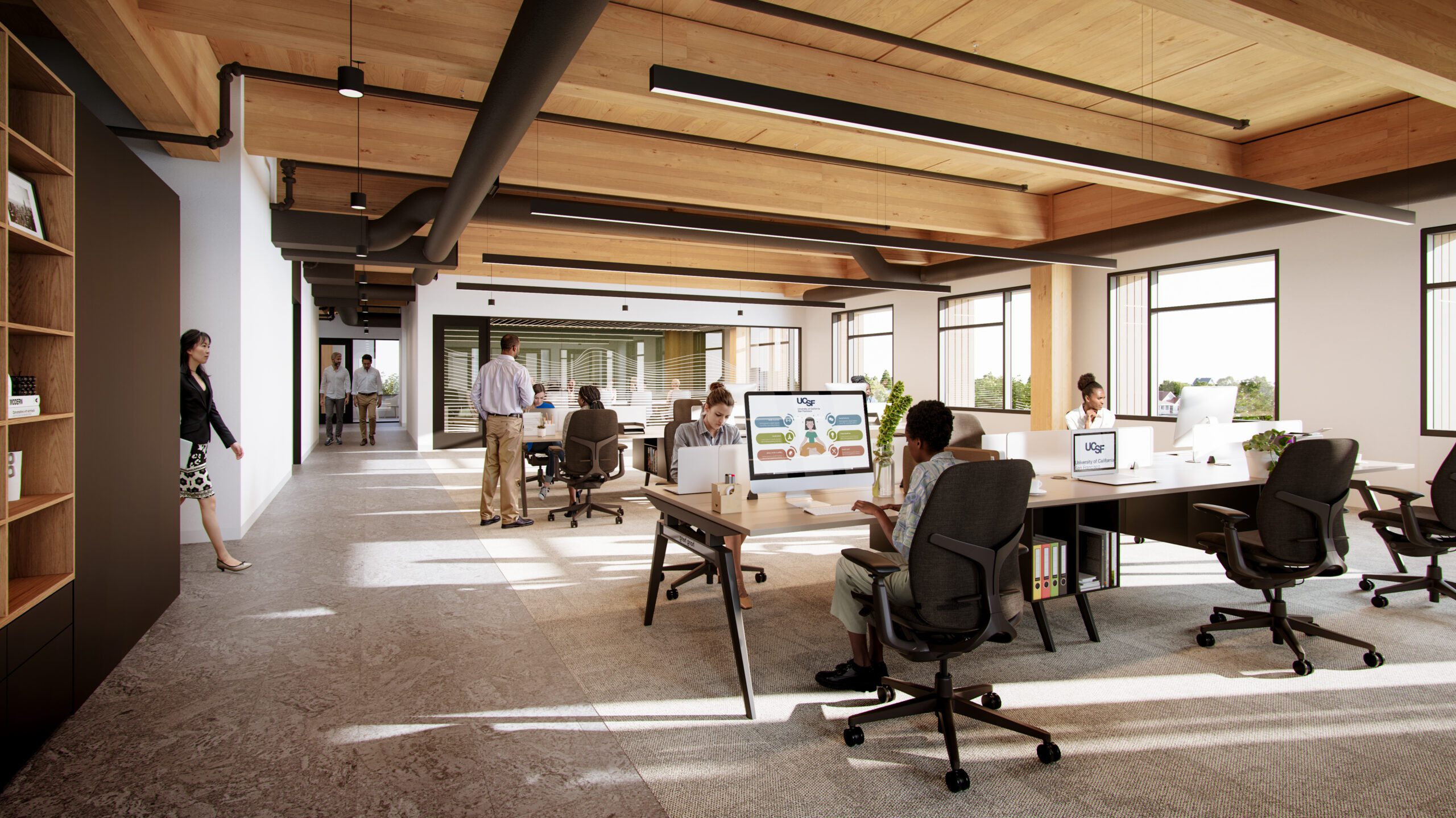 Open-plan office with wooden beams, desks, and people working. Collaboration in UCSF's mass timber project, aided by preconstruction software.