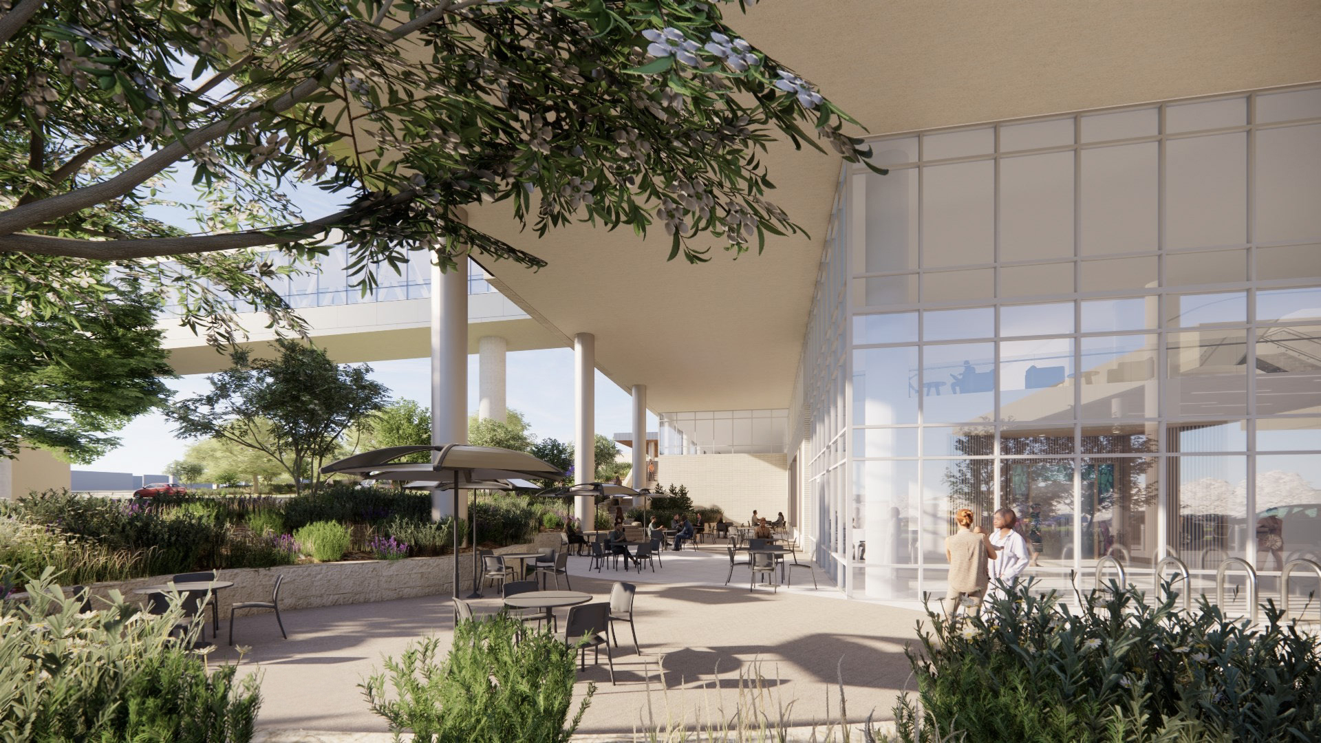 Outdoor patio area with tables, chairs, and landscaping near a modern building.